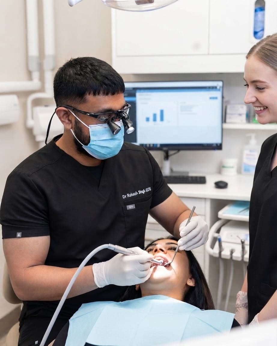 Dr Rakesh Singh treating a patient in the surgery at the practice, with a dental nurse assisting.